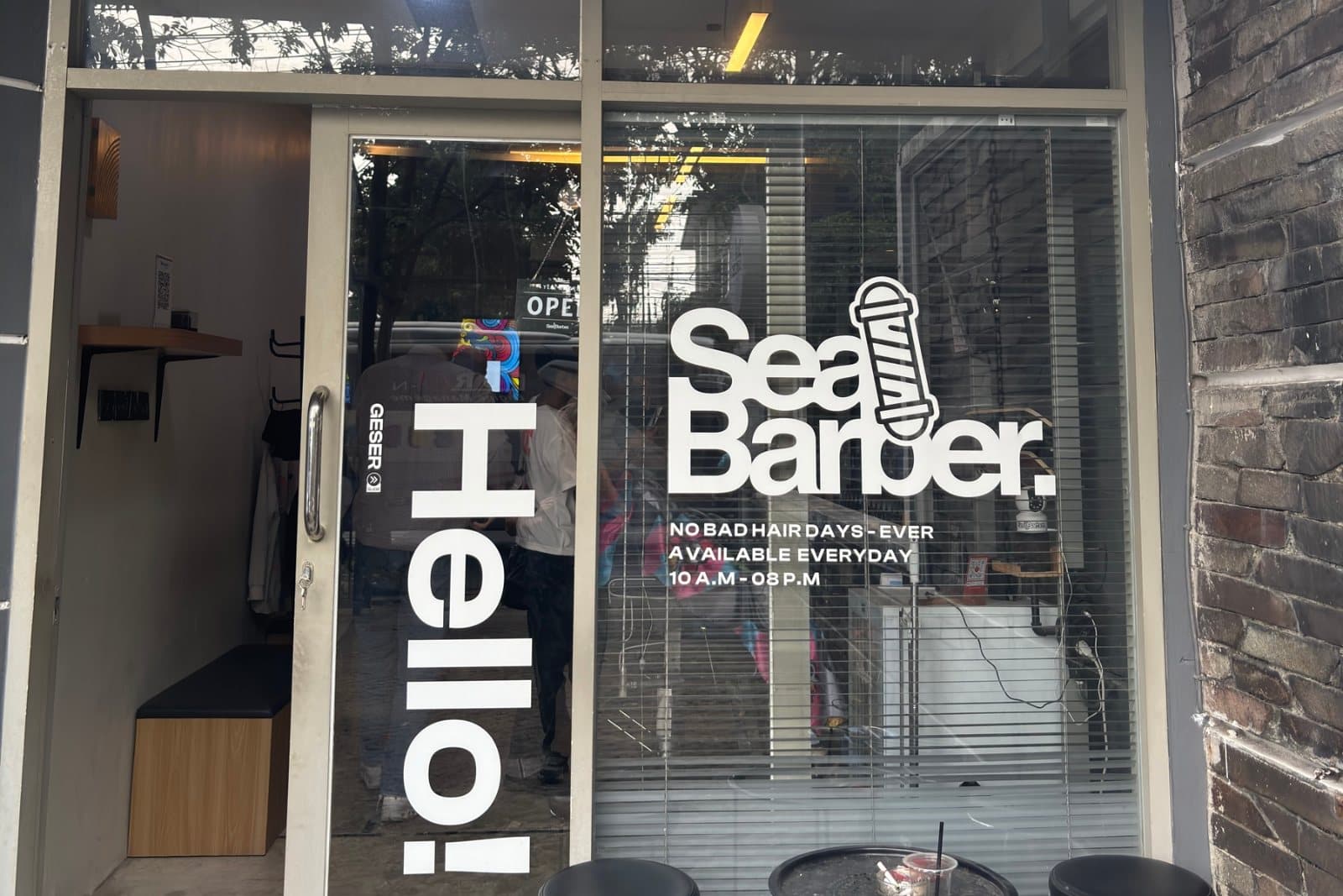 Tampak depan gerai SeaBarber dengan kaca bertuliskan Hello dan logo SeaBarber
