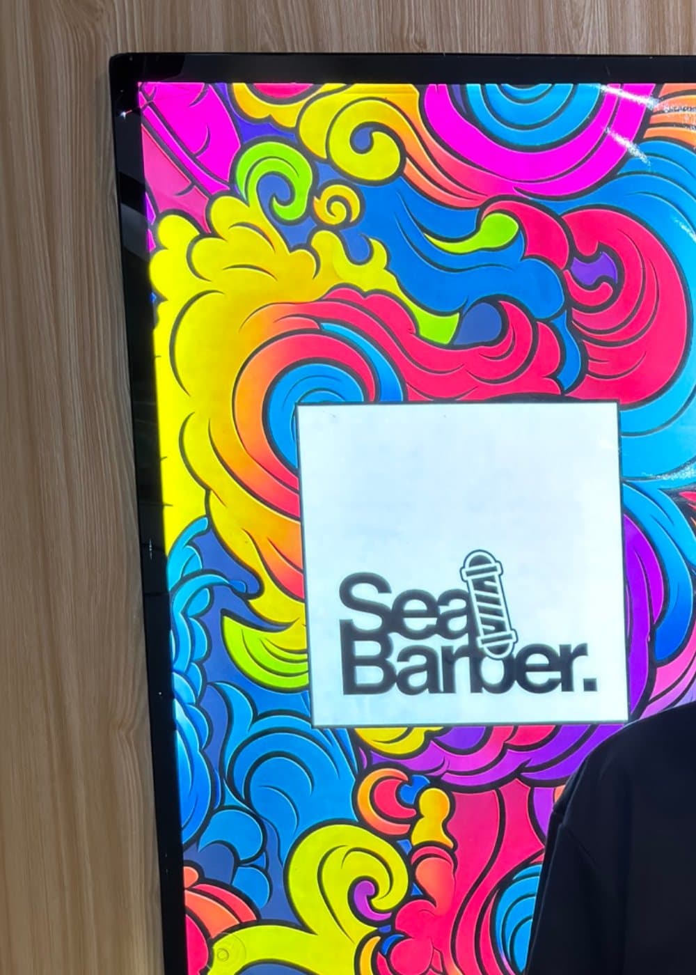 Papan logo SeaBarber dan jam dinding di dalam gerai