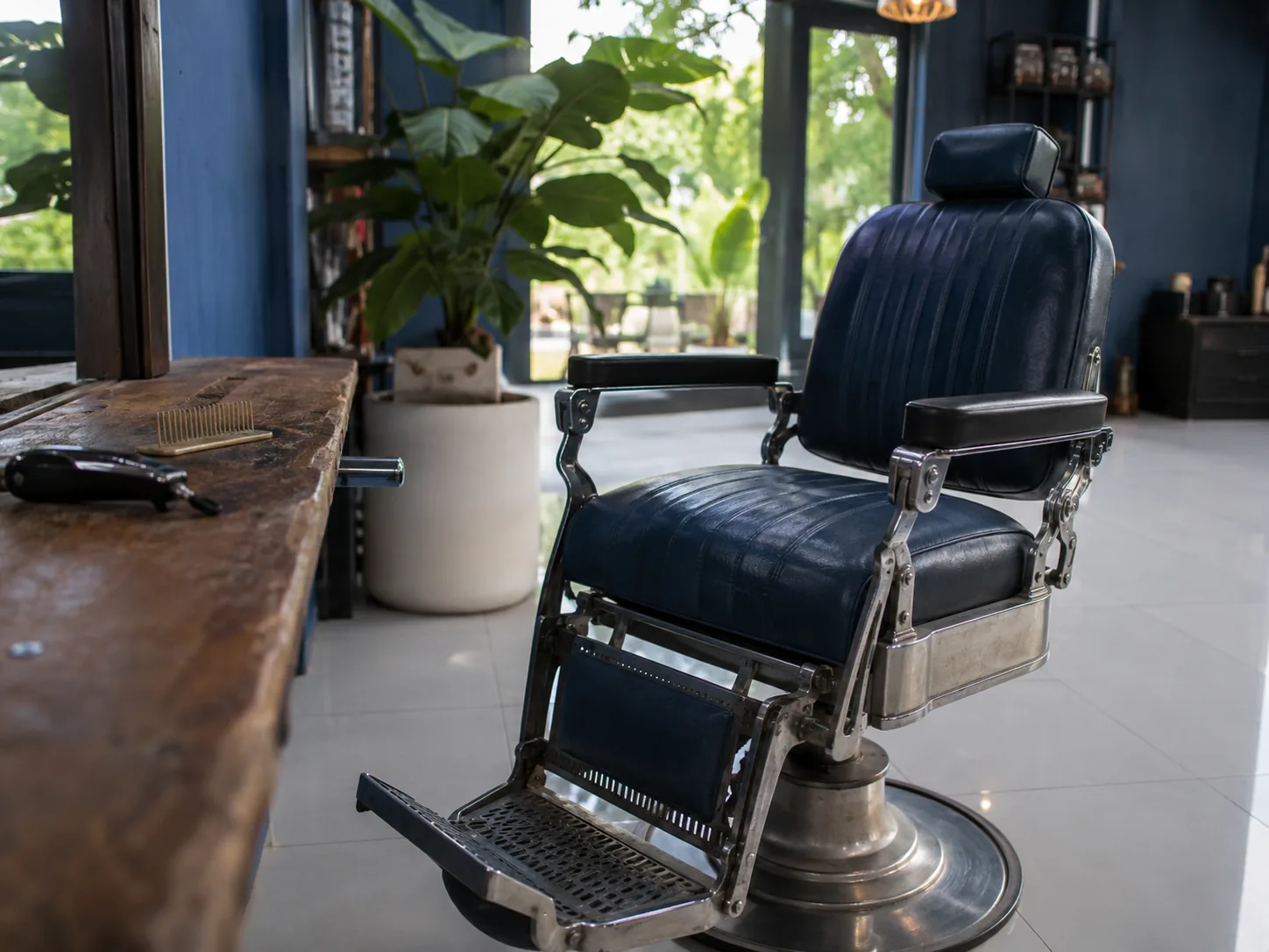 Kursi barber klasik dari kulit di depan meja kayu berisi sisir dan alat cukur.