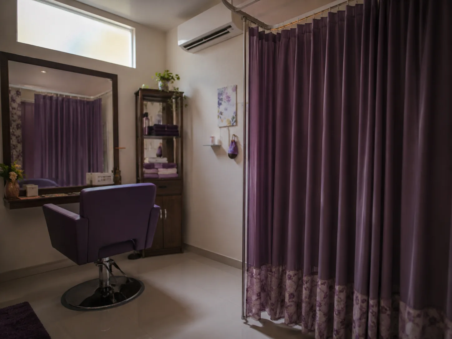 Ruang perawatan privat di salon muslimah dengan tirai penutup, satu kursi styling, dan cermin.