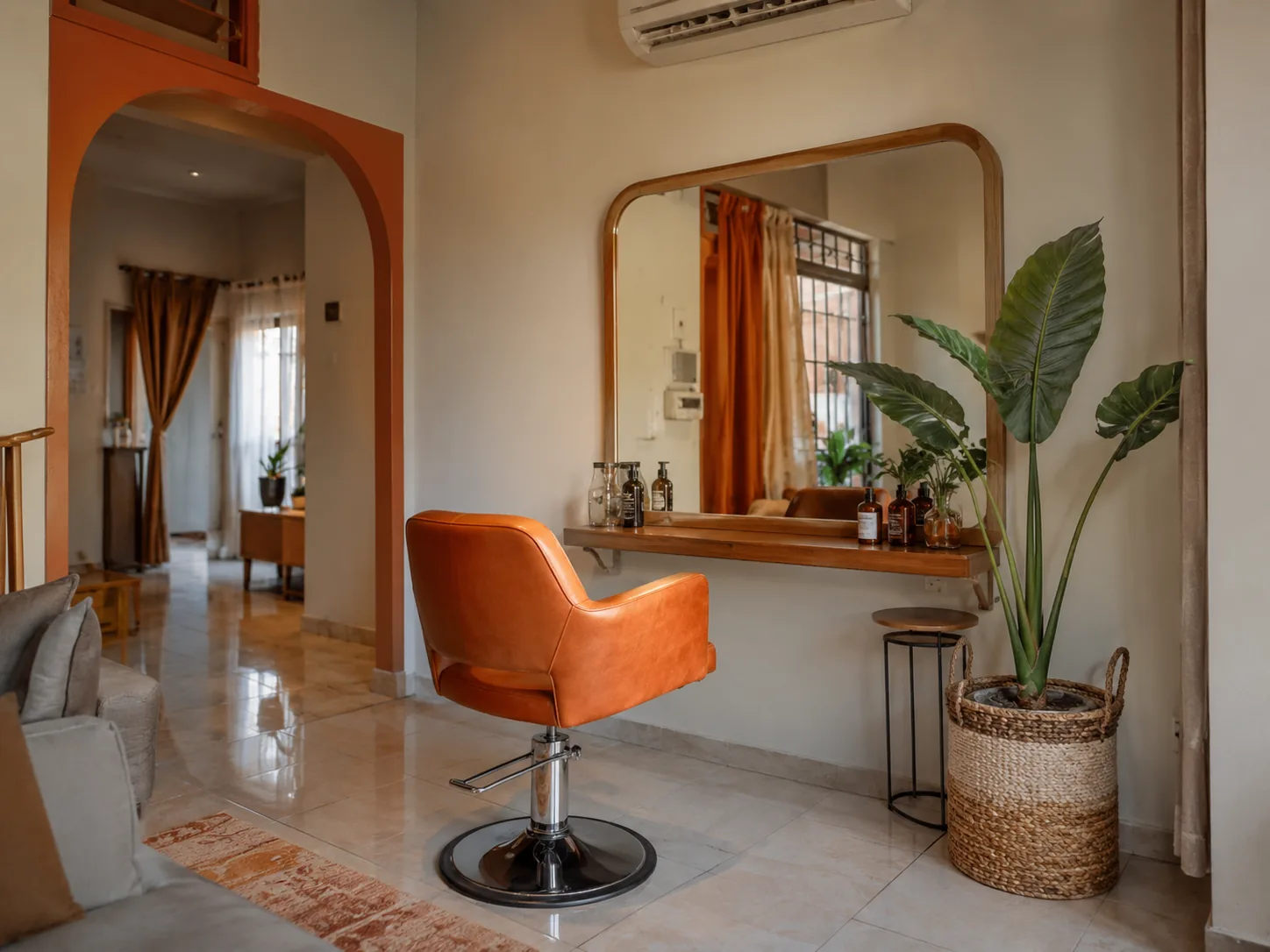 Satu kursi styling dan cermin yang ditata di ruang depan rumah, dengan ruang keluarga terlihat di baliknya.